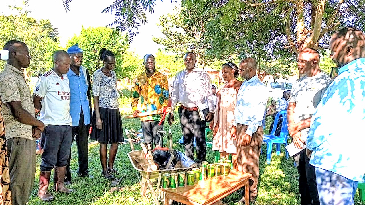 The LC5 Chairman Buyende District handing over items distributed by CHAIN Directors to CVCs in Busambira Community, Buyende Town Council. On right is SNV Busoga Regional Coordinator, Mr. Aggrey Ntakimanye.